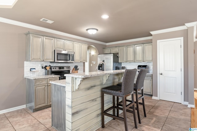 kitchen with stainless steel appliances, arched walkways, ornamental molding, and a breakfast bar