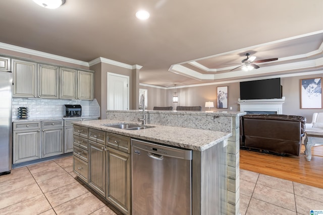 kitchen featuring appliances with stainless steel finishes, open floor plan, a tray ceiling, a sink, and light tile patterned flooring