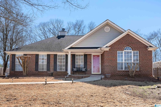 ranch-style home with a shingled roof, a chimney, and brick siding