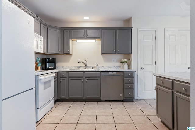 kitchen with light tile patterned floors, recessed lighting, gray cabinetry, a sink, and white appliances