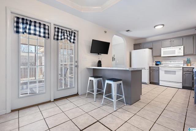 kitchen with light tile patterned floors, white appliances, a kitchen breakfast bar, light countertops, and gray cabinets