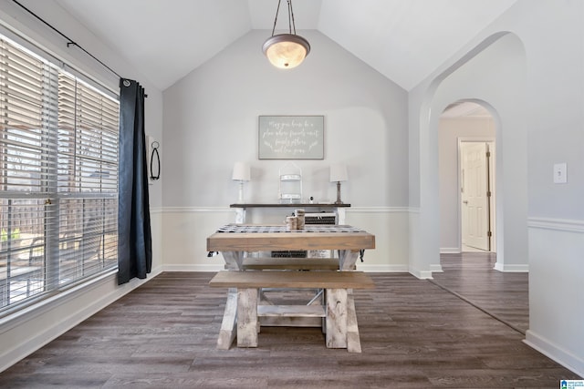 unfurnished dining area with arched walkways, wood finished floors, lofted ceiling, and baseboards