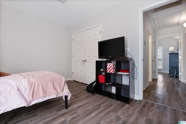 bedroom featuring wood finished floors, visible vents, baseboards, a closet, and attic access