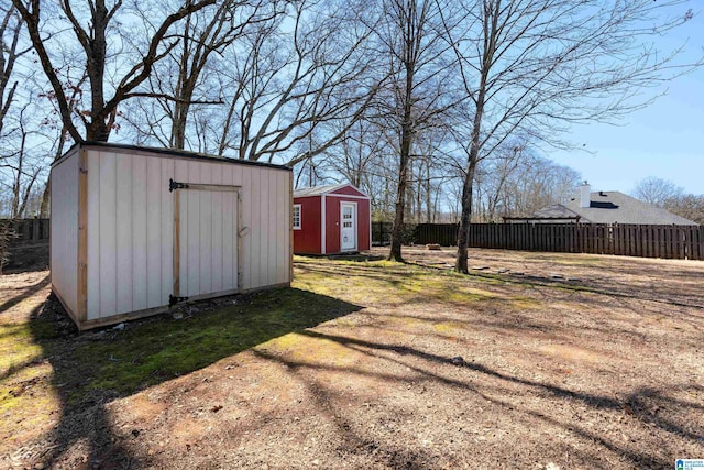 view of yard with a storage shed, fence, and an outbuilding