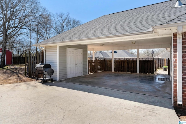 garage featuring driveway, fence, and an attached carport