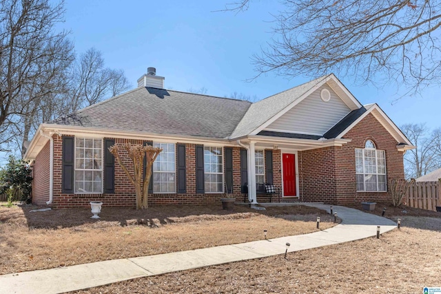 view of front of property featuring a shingled roof, brick siding, fence, and a chimney