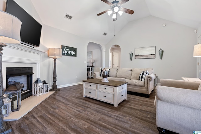 living room featuring dark wood-style floors, arched walkways, a fireplace with raised hearth, and visible vents