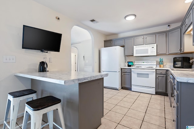 kitchen featuring white appliances, visible vents, a peninsula, gray cabinets, and a sink