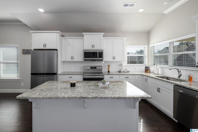 kitchen with appliances with stainless steel finishes, a sink, visible vents, and a kitchen breakfast bar