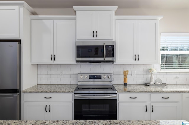 kitchen featuring stainless steel appliances, decorative backsplash, and white cabinets