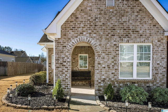 view of front of home featuring fence and brick siding