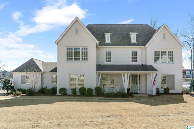 view of front of property with covered porch, a shingled roof, and brick siding