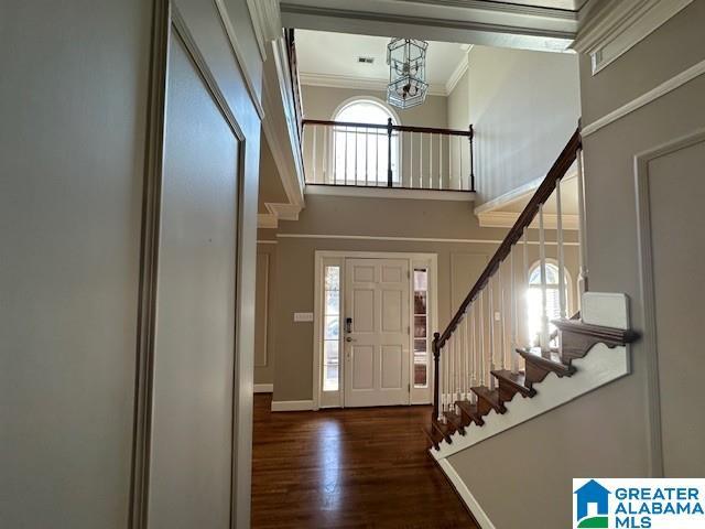 entryway with baseboards, ornamental molding, wood finished floors, stairs, and a high ceiling