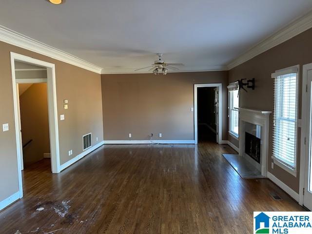 unfurnished living room featuring crown molding, a fireplace, visible vents, and wood finished floors