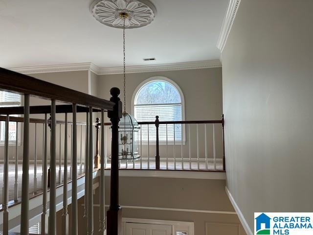 interior space with baseboards, visible vents, and crown molding