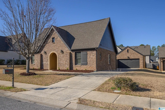 view of front facade featuring a garage, driveway, brick siding, and a shingled roof