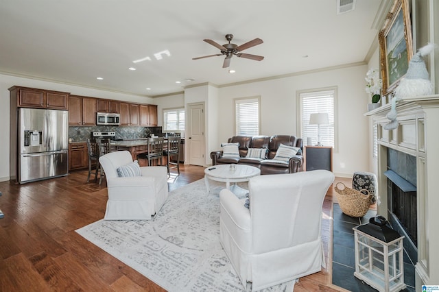 living room featuring dark wood-style flooring, a fireplace, visible vents, and crown molding