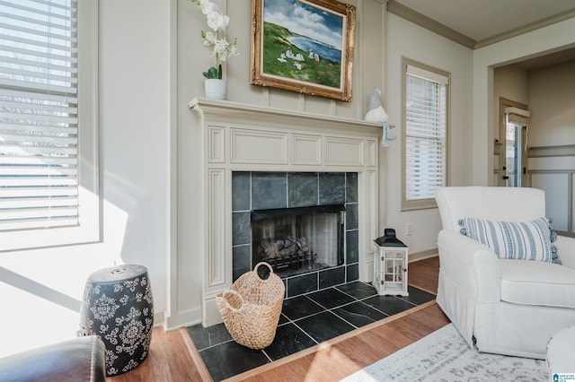 living room with ornamental molding, a fireplace, baseboards, and wood finished floors