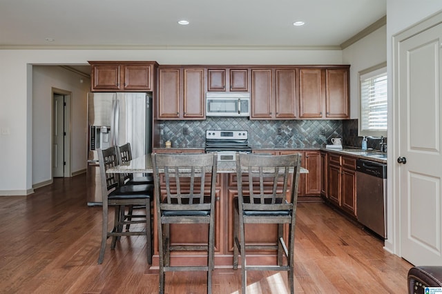 kitchen featuring a center island, dark wood-style flooring, a breakfast bar area, stainless steel appliances, and a sink