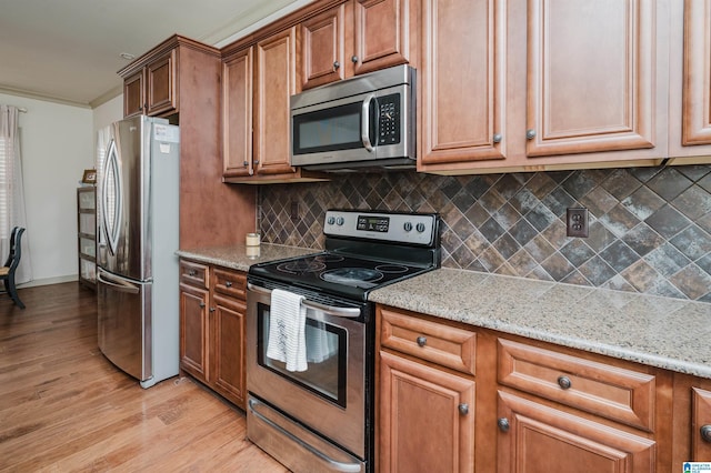 kitchen with light stone counters, stainless steel appliances, backsplash, brown cabinets, and light wood finished floors