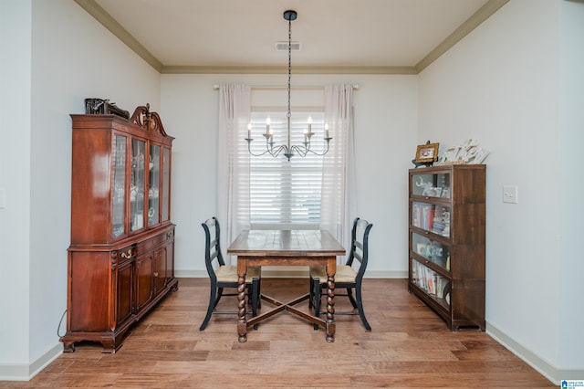 dining space with light wood-style floors, crown molding, visible vents, and a notable chandelier