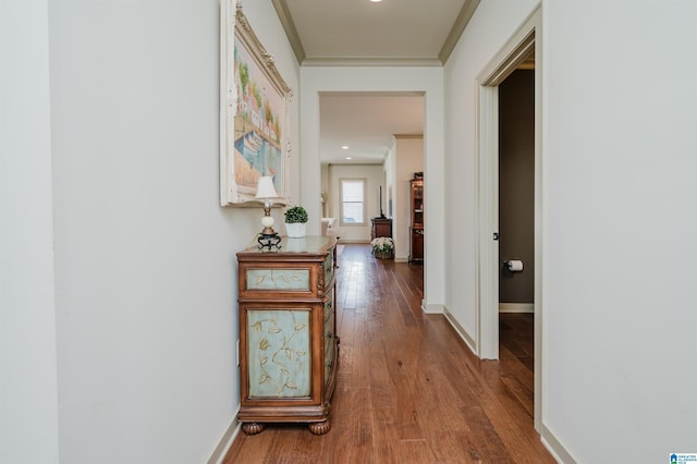 hallway featuring ornamental molding, wood-type flooring, and baseboards