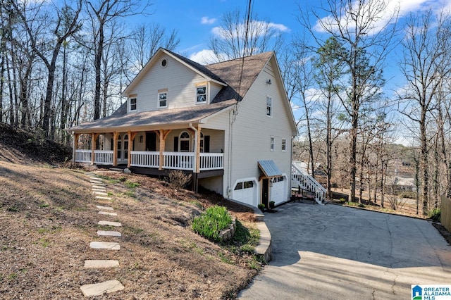 view of front of home with a porch, driveway, stairway, and a garage