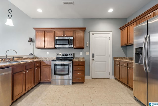 kitchen featuring brown cabinetry, visible vents, stainless steel appliances, and a sink