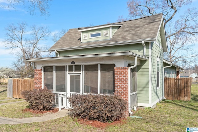 exterior space with a sunroom, fence, a lawn, and brick siding