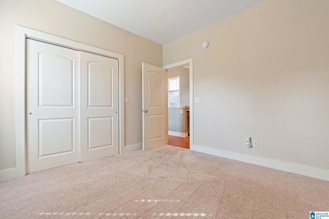 unfurnished bedroom featuring carpet floors, a closet, and baseboards