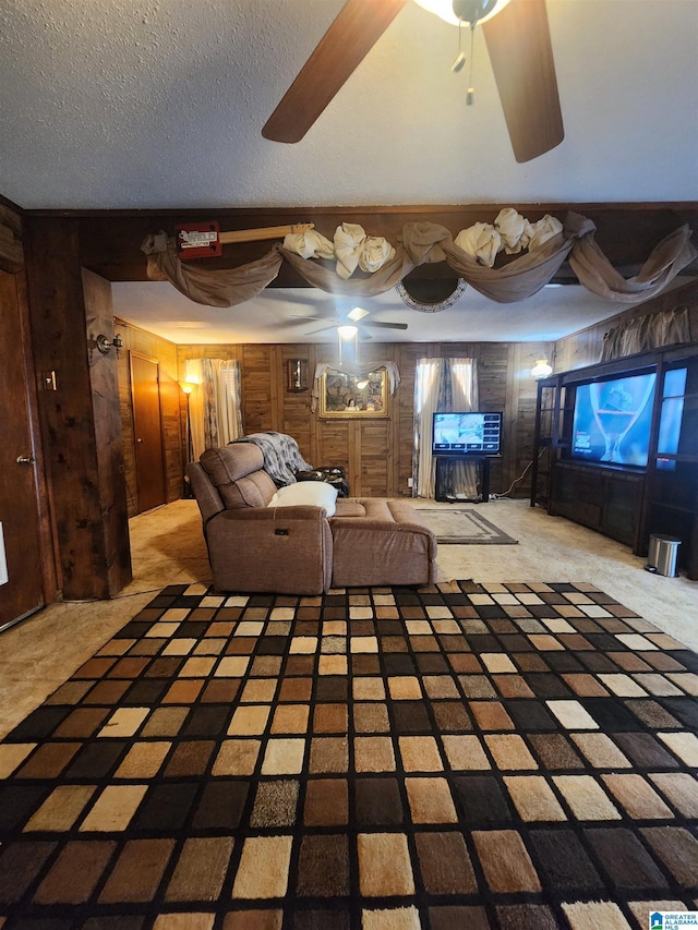 unfurnished living room featuring a textured ceiling, ceiling fan, wood walls, and carpet