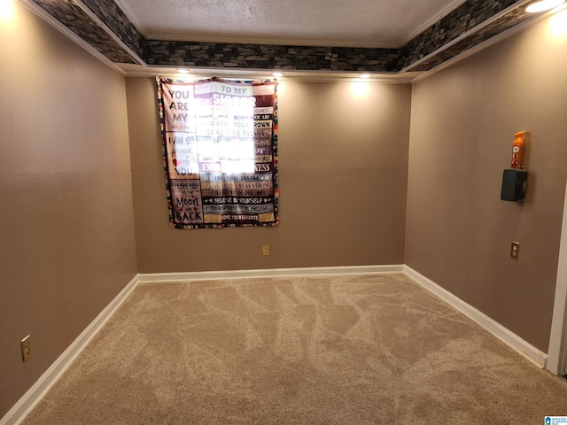 empty room featuring carpet floors, crown molding, a textured ceiling, and baseboards