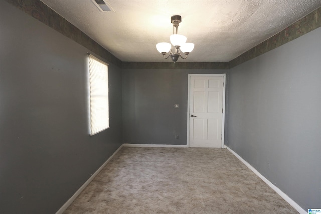 carpeted empty room with an inviting chandelier, visible vents, baseboards, and a textured ceiling