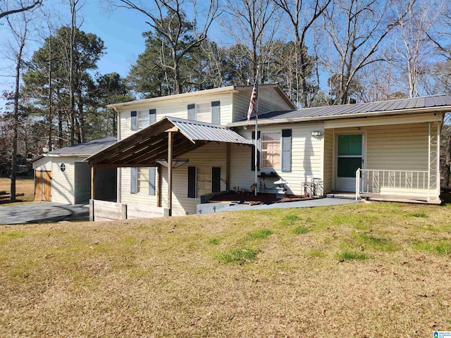 back of house featuring covered porch, metal roof, and a lawn