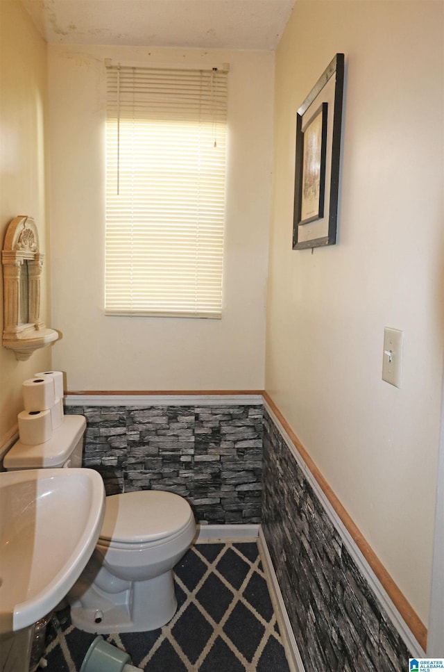 bathroom with toilet, a sink, and wainscoting