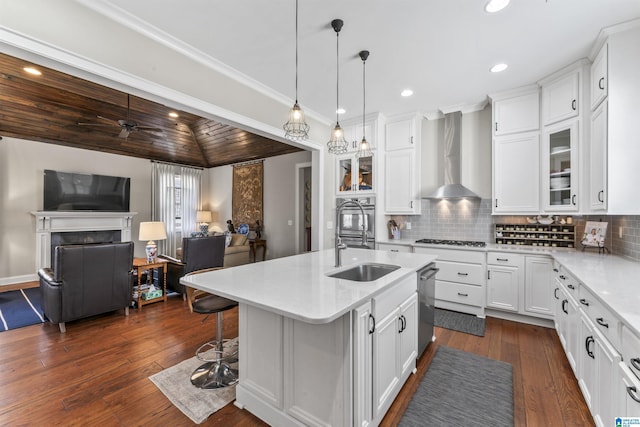 kitchen featuring gas cooktop, a fireplace, a sink, open floor plan, and wall chimney exhaust hood