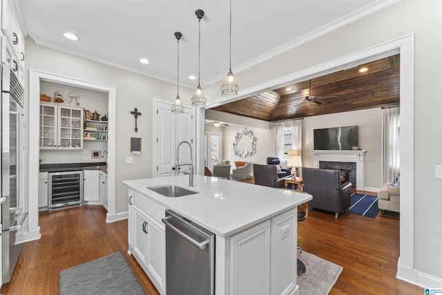 kitchen with beverage cooler, white cabinets, stainless steel appliances, a fireplace, and a sink