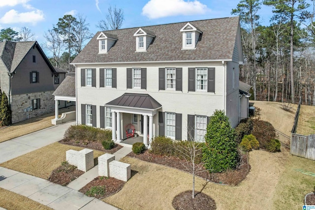 view of front facade featuring driveway, a porch, fence, and brick siding