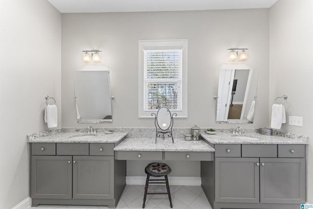 bathroom with baseboards, two vanities, and a sink