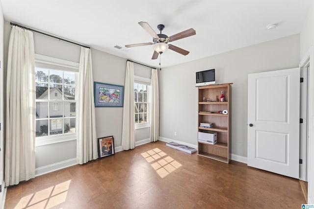 empty room with a wealth of natural light, visible vents, baseboards, and wood finished floors