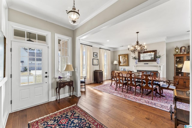 entrance foyer featuring baseboards, wood-type flooring, a chandelier, and crown molding