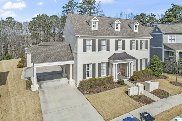 view of front of house with a front yard, concrete driveway, and roof with shingles