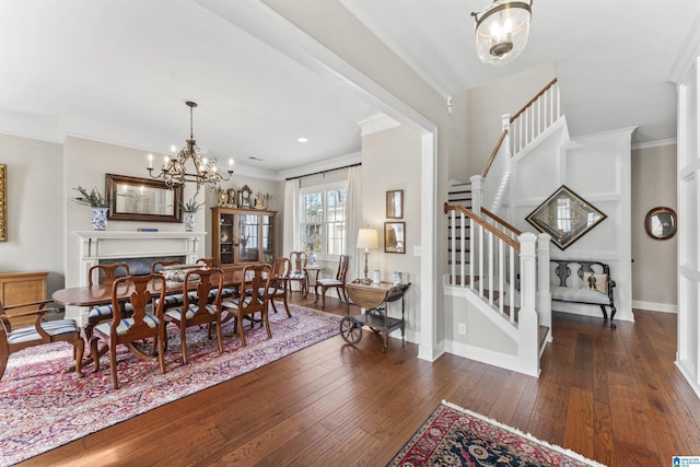 dining area with hardwood / wood-style flooring, a notable chandelier, ornamental molding, baseboards, and stairs