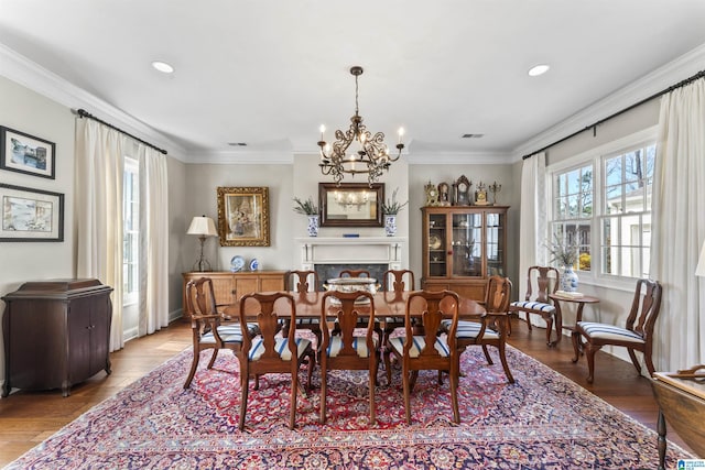 dining space with a notable chandelier, recessed lighting, wood finished floors, and crown molding