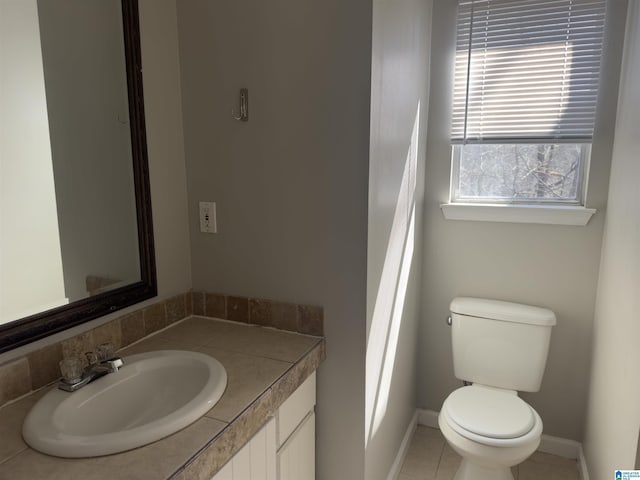 bathroom with tile patterned flooring, baseboards, vanity, and toilet