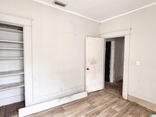 unfurnished bedroom with visible vents, wood finished floors, and ornamental molding