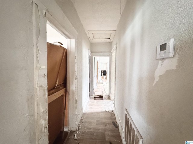 corridor with attic access, visible vents, and a textured wall