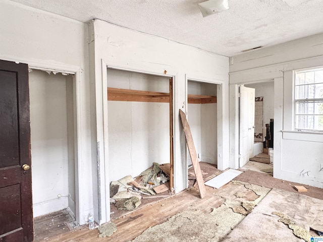 bedroom featuring a textured ceiling, connected bathroom, visible vents, and multiple closets