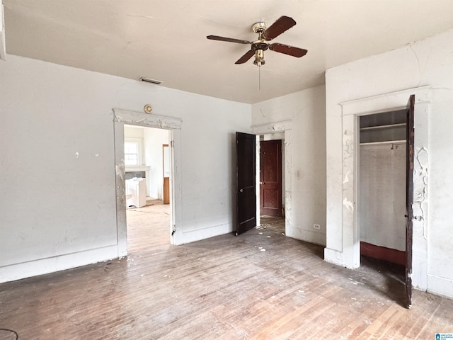 unfurnished bedroom featuring ceiling fan, visible vents, a closet, and wood finished floors