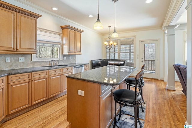 kitchen featuring a sink, ornamental molding, stainless steel dishwasher, a kitchen bar, and ornate columns